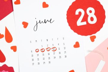 Artistic still life of a June calendar with heart and blood drop cutouts symbolizing the menstrual cycle.