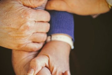 person in blue long sleeve shirt holding babys hand